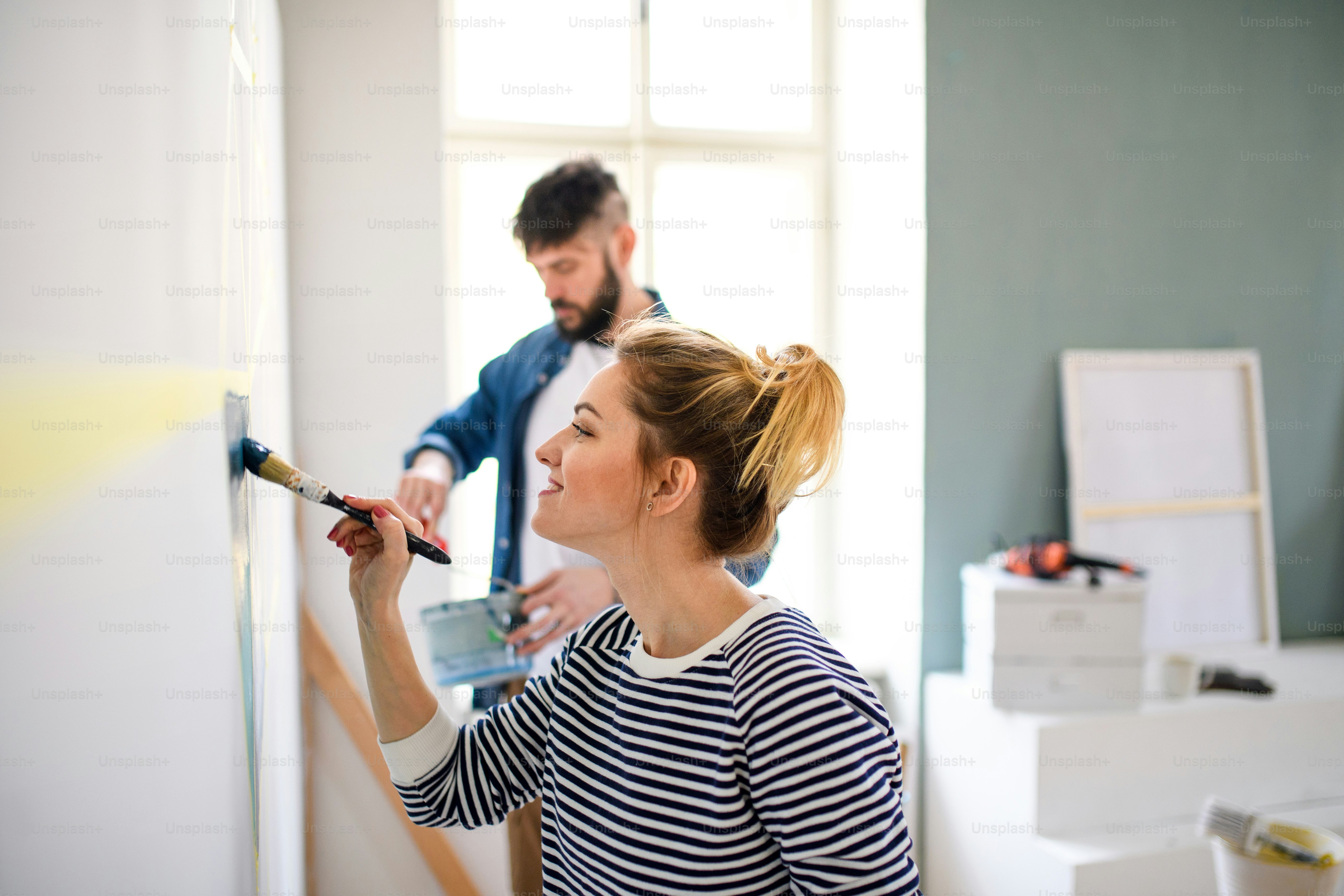 Happy mid adults couple painting wall indoors at home, relocation and diy concept
